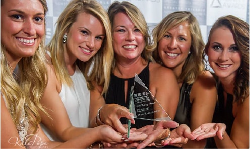 Group of happy women holding trophy created by FiveStar Awards & Engraving in Cary NC